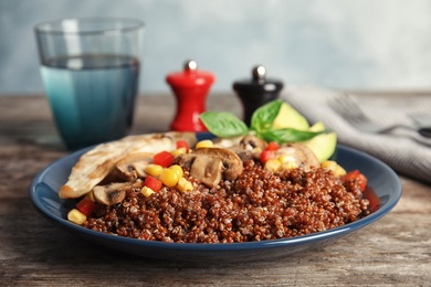 Plate with quinoa and garnish on table, closeup