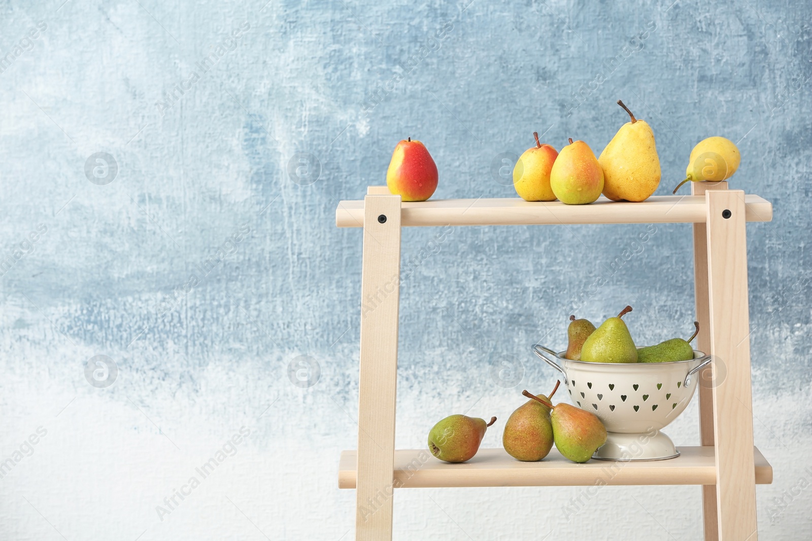 Photo of Shelving unit with ripe pears on color background. Space for text