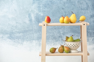 Shelving unit with ripe pears on color background. Space for text