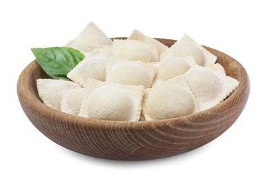 Photo of Uncooked ravioli and basil in wooden bowl on white background