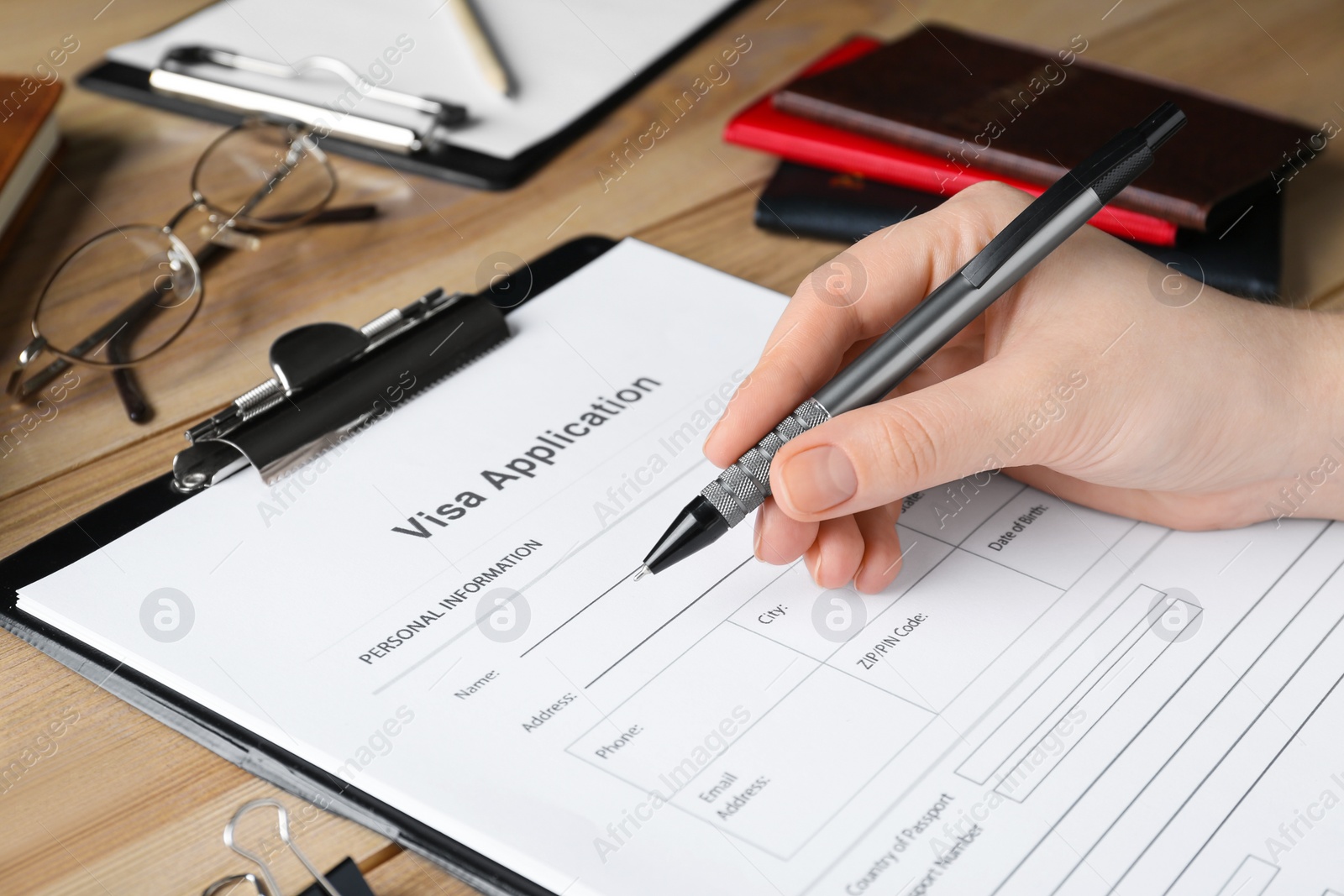 Photo of Woman filling visa application form at wooden table, closeup