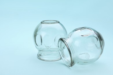 Photo of Glass cups on light blue background, closeup with space for text. Cupping therapy