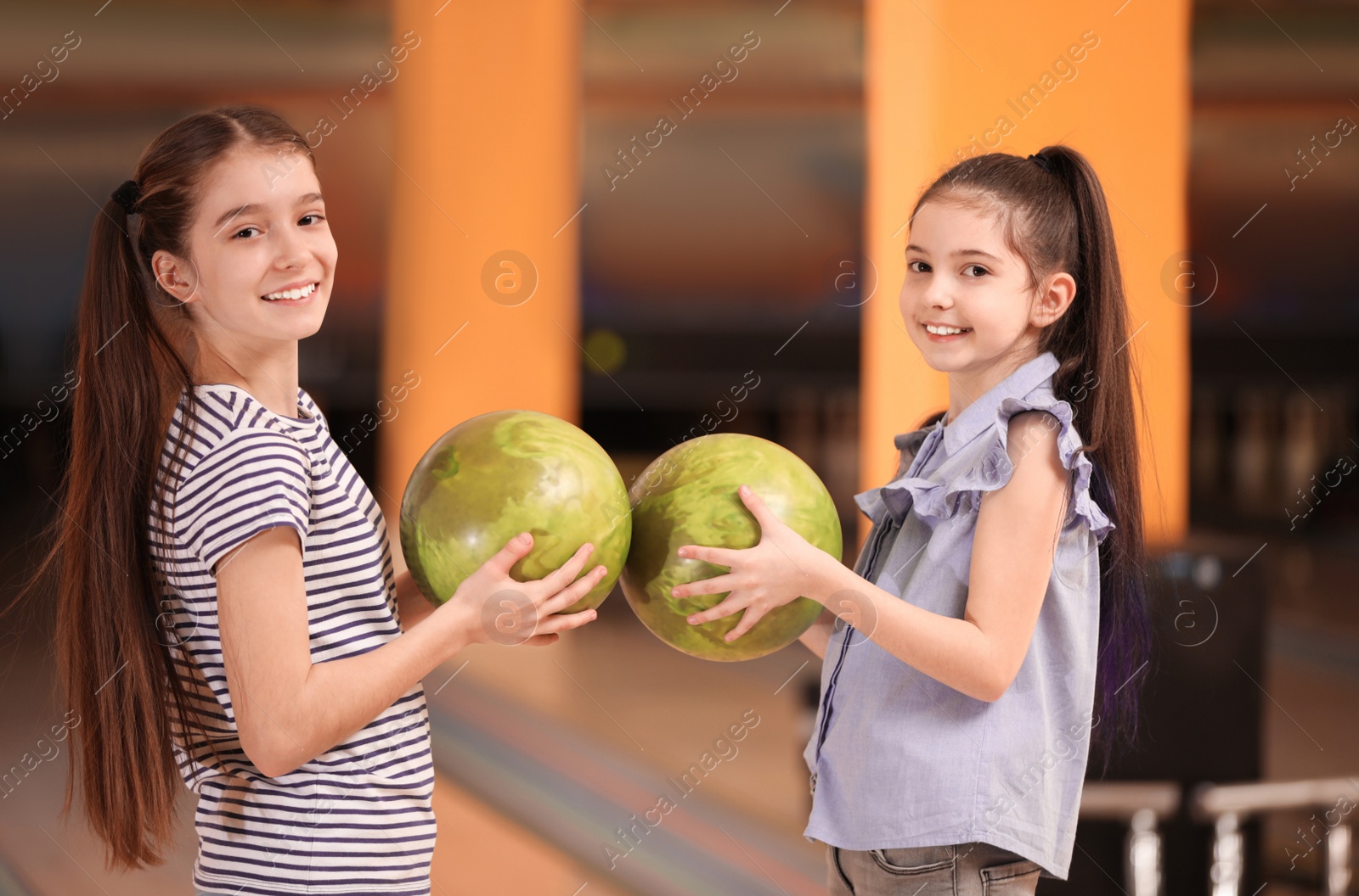 Photo of Happy girls with balls in bowling club