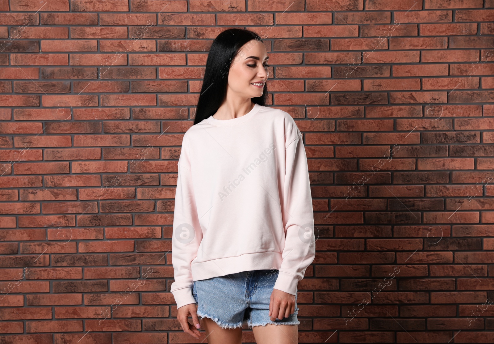 Photo of Portrait of young woman in sweater at brick wall. Mock up for design