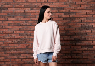 Photo of Portrait of young woman in sweater at brick wall. Mock up for design