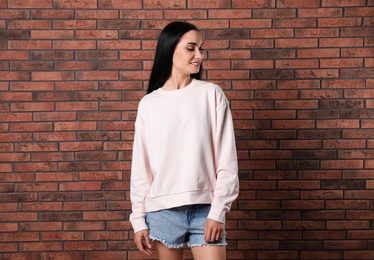 Portrait of young woman in sweater at brick wall. Mock up for design