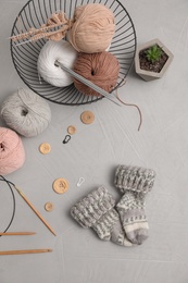 Photo of Flat lay composition with threads and knitted mittens on grey background. Engaging hobby