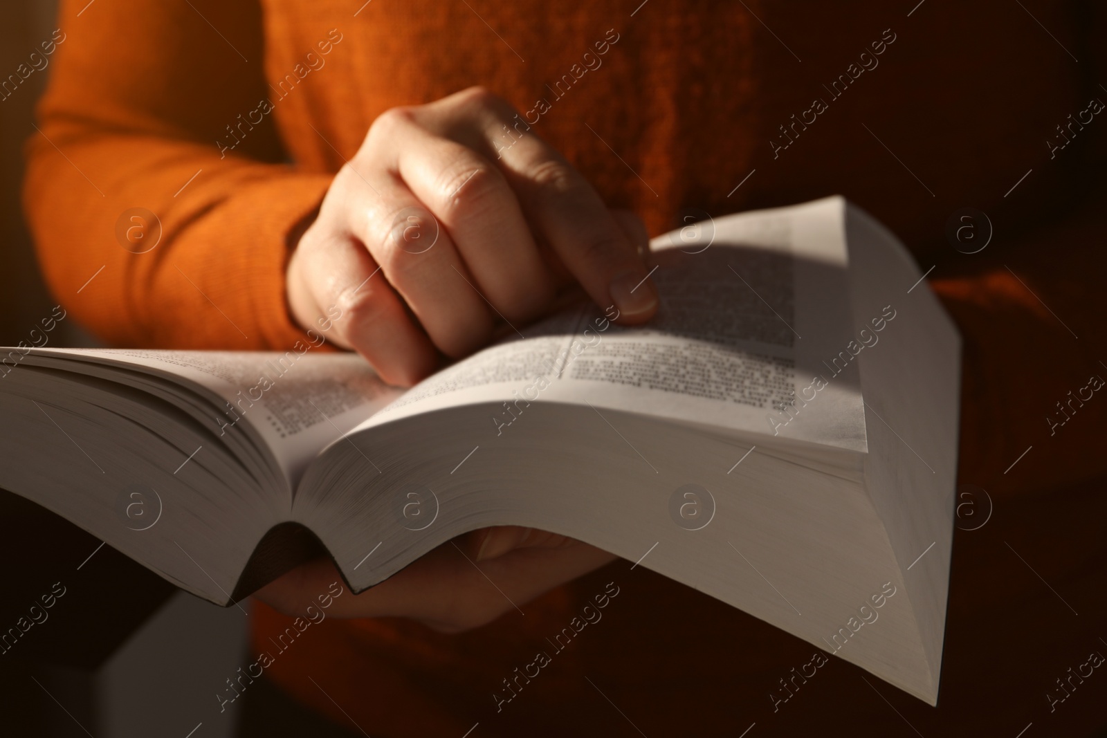 Photo of Woman reading Bible against black background, closeup