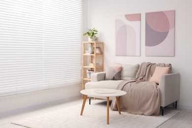 Photo of Stylish living room interior with sofa, coffee table and wooden shelf. Space for text