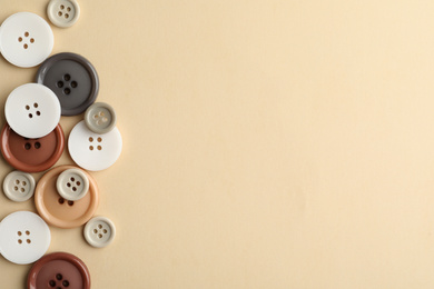 Photo of Many colorful sewing buttons on beige background, flat lay. Space for text