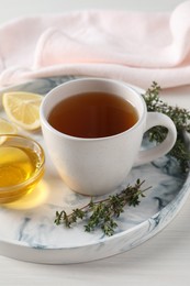 Photo of Aromatic herbal tea with thyme, honey and lemon on white wooden table