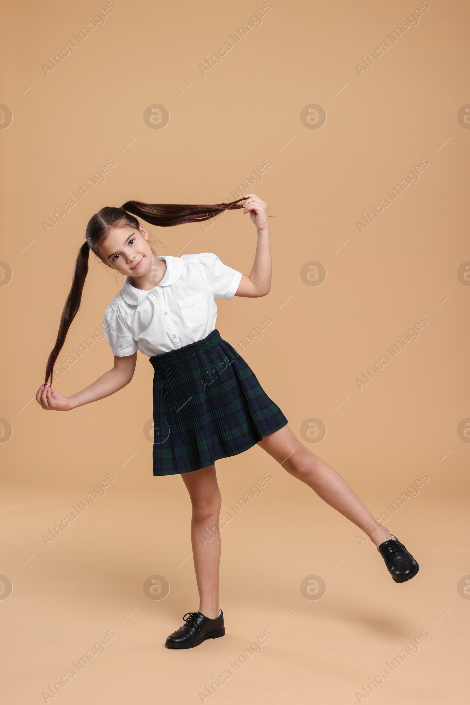 Photo of Cute schoolgirl on beige background, space for text