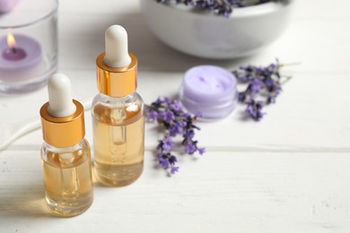 Photo of Composition with bottles of essential oil and lavender flowers on white wooden table. Space for text