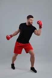 Photo of Man in boxing gloves fighting on grey background