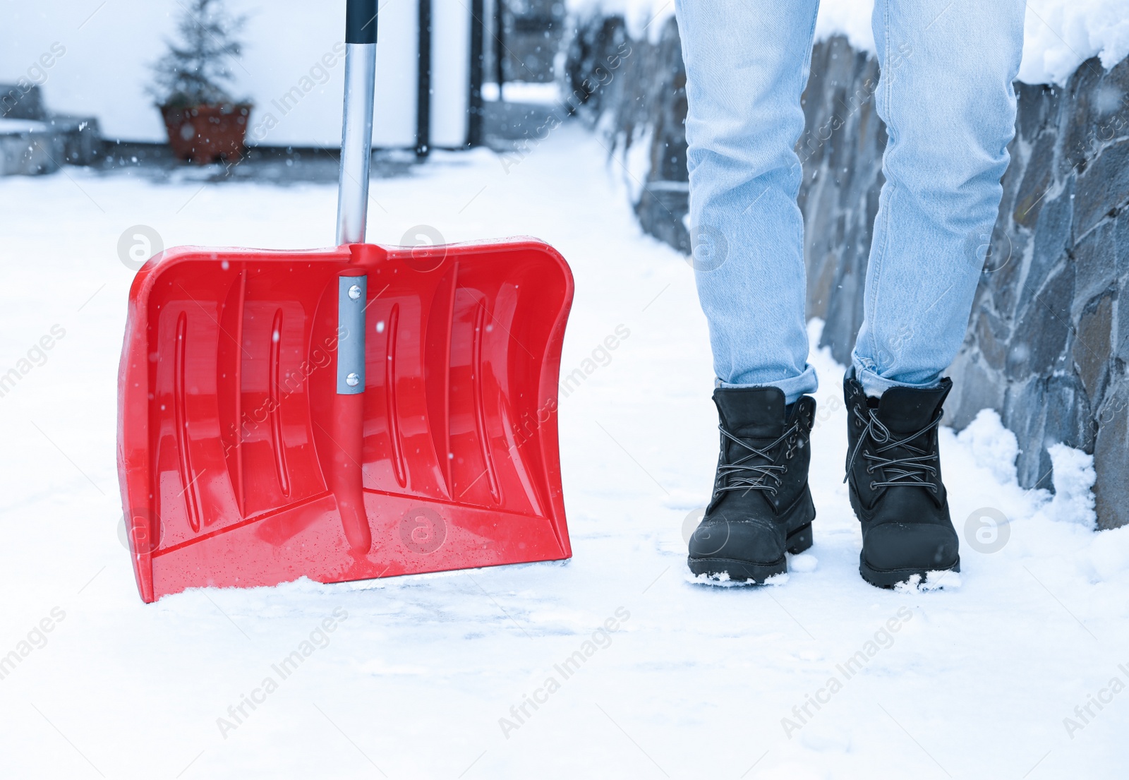 Photo of Man with red snow shovel outdoors. Winter weather