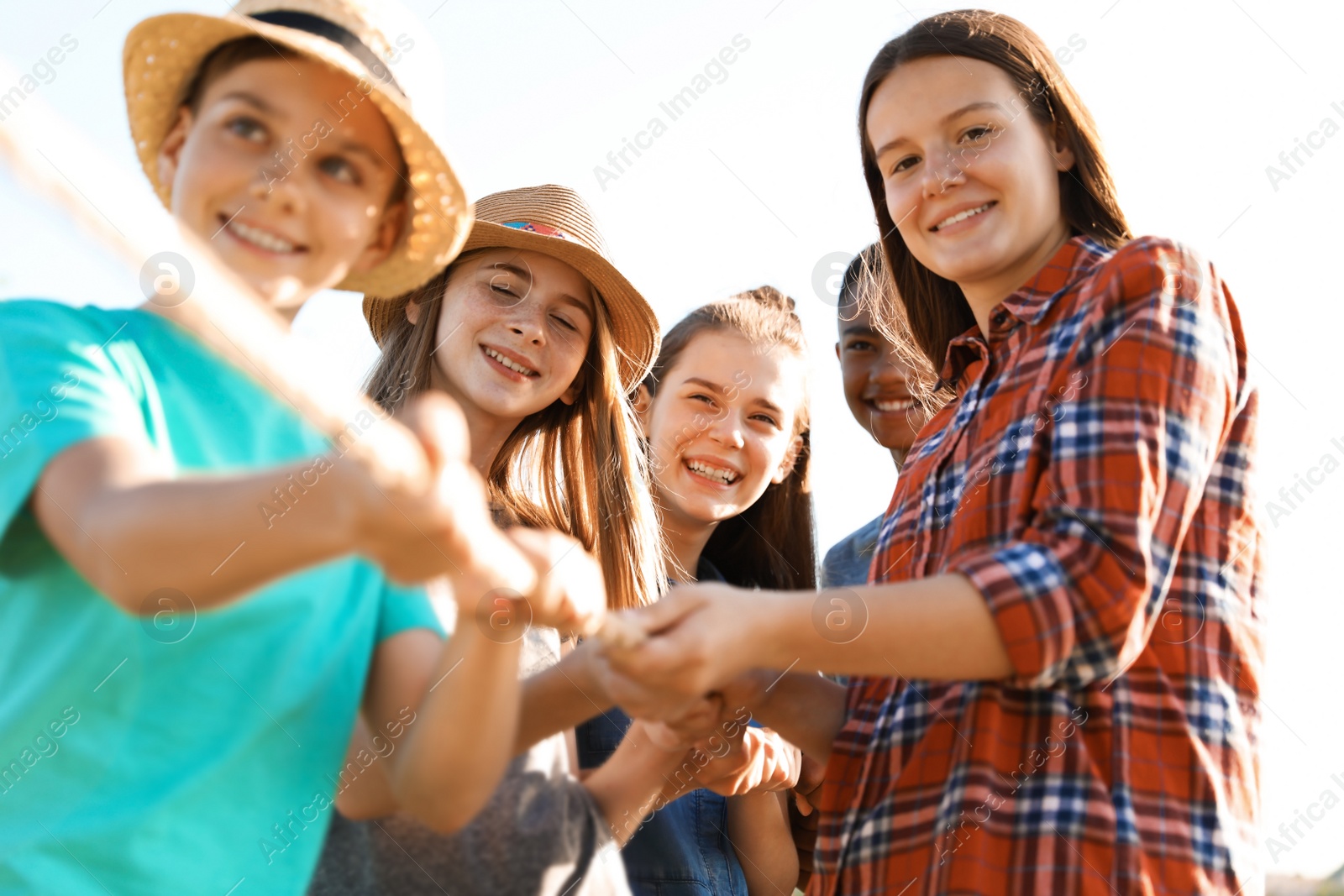 Photo of Group of children pulling rope during tug of war game outdoors. Summer camp