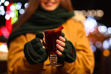 Woman with tasty mulled wine at winter fair, closeup