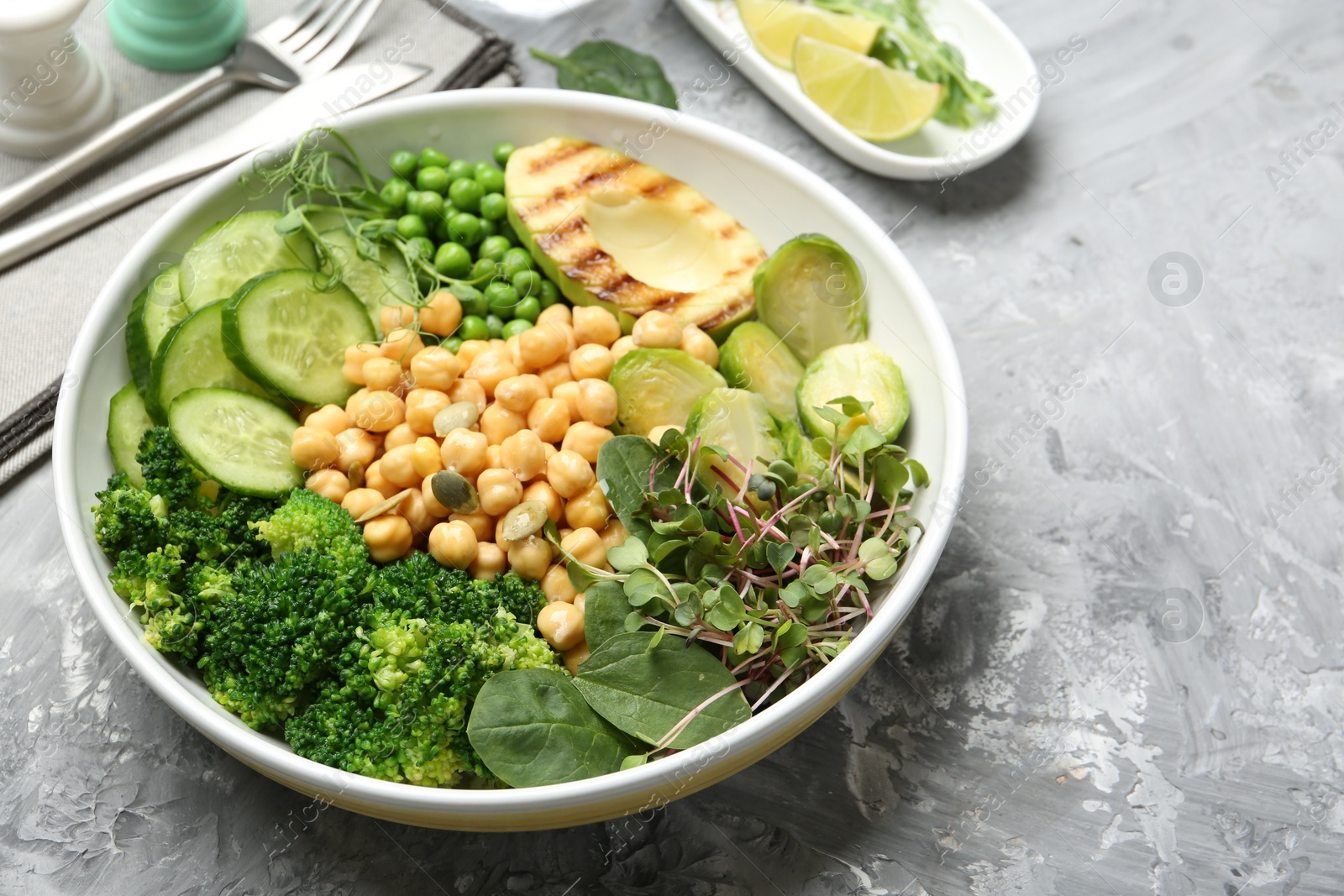 Photo of Healthy meal. Tasty vegetables and chickpeas in bowl on grey table