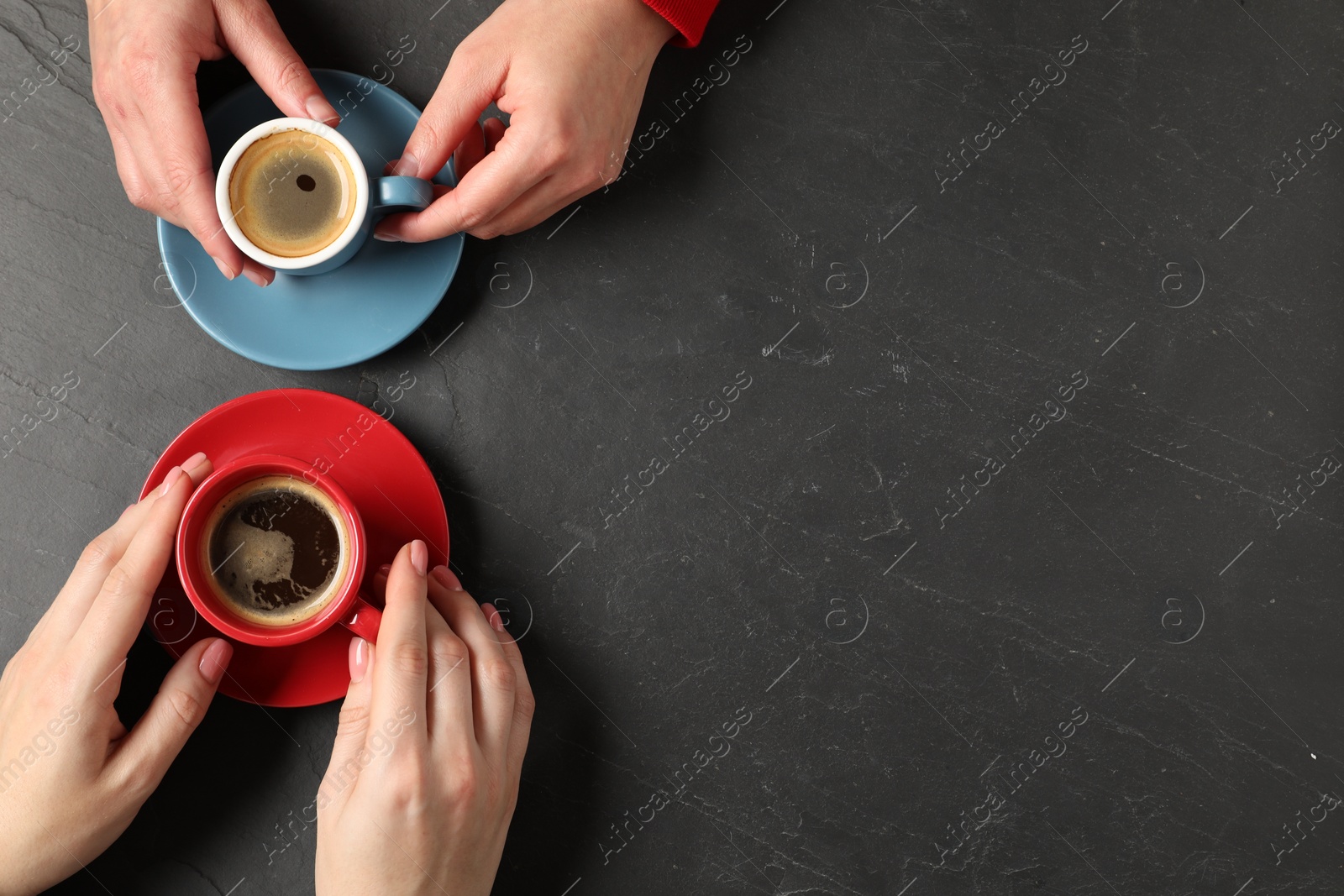 Photo of Women having coffee break at dark textured table, top view. Space for text