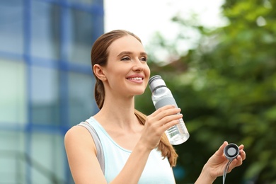 Young woman with bottle of water outdoors. Refreshing drink