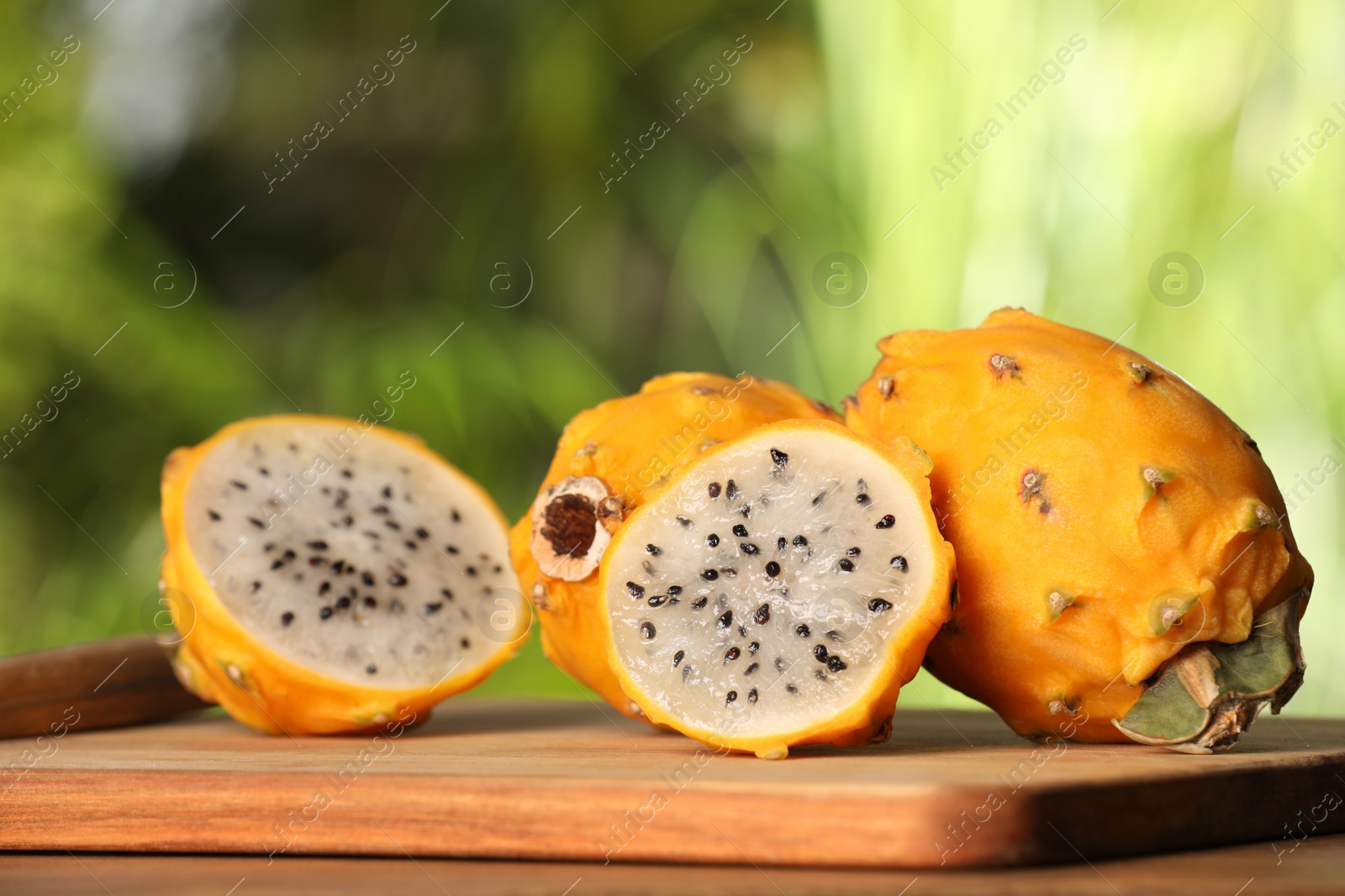 Photo of Delicious cut and whole dragon fruits (pitahaya) on wooden table