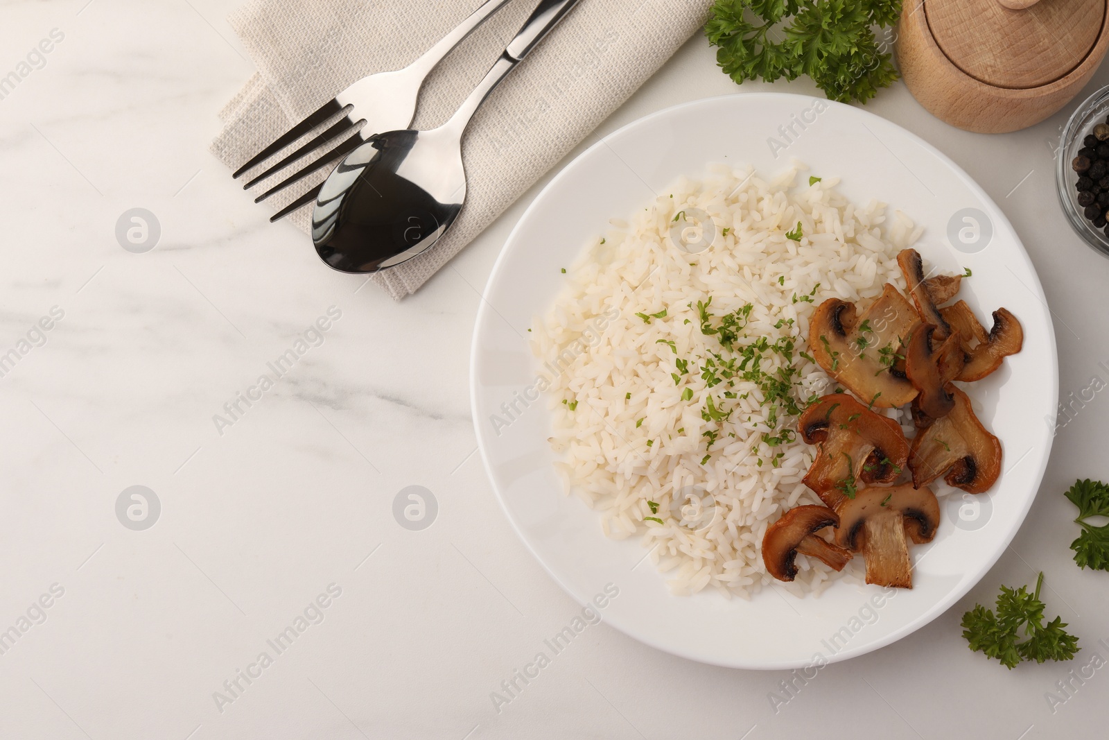 Photo of Delicious rice with parsley and mushrooms served on white marble table, flat lay. Space for text