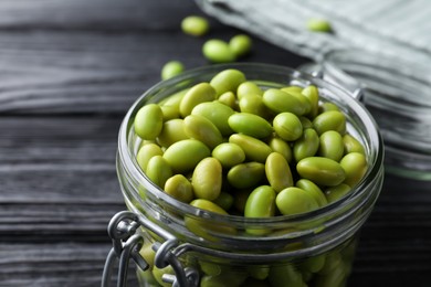 Jar of edamame beans on black wooden table, closeup