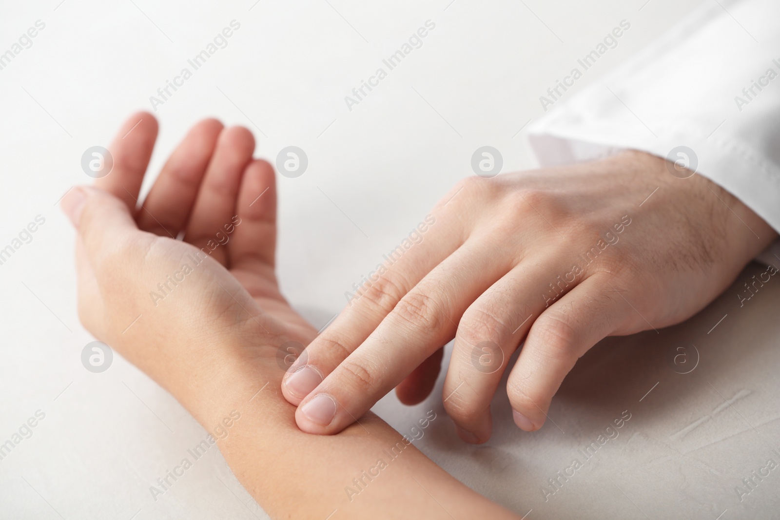 Photo of Doctor checking patient's pulse on table, closeup