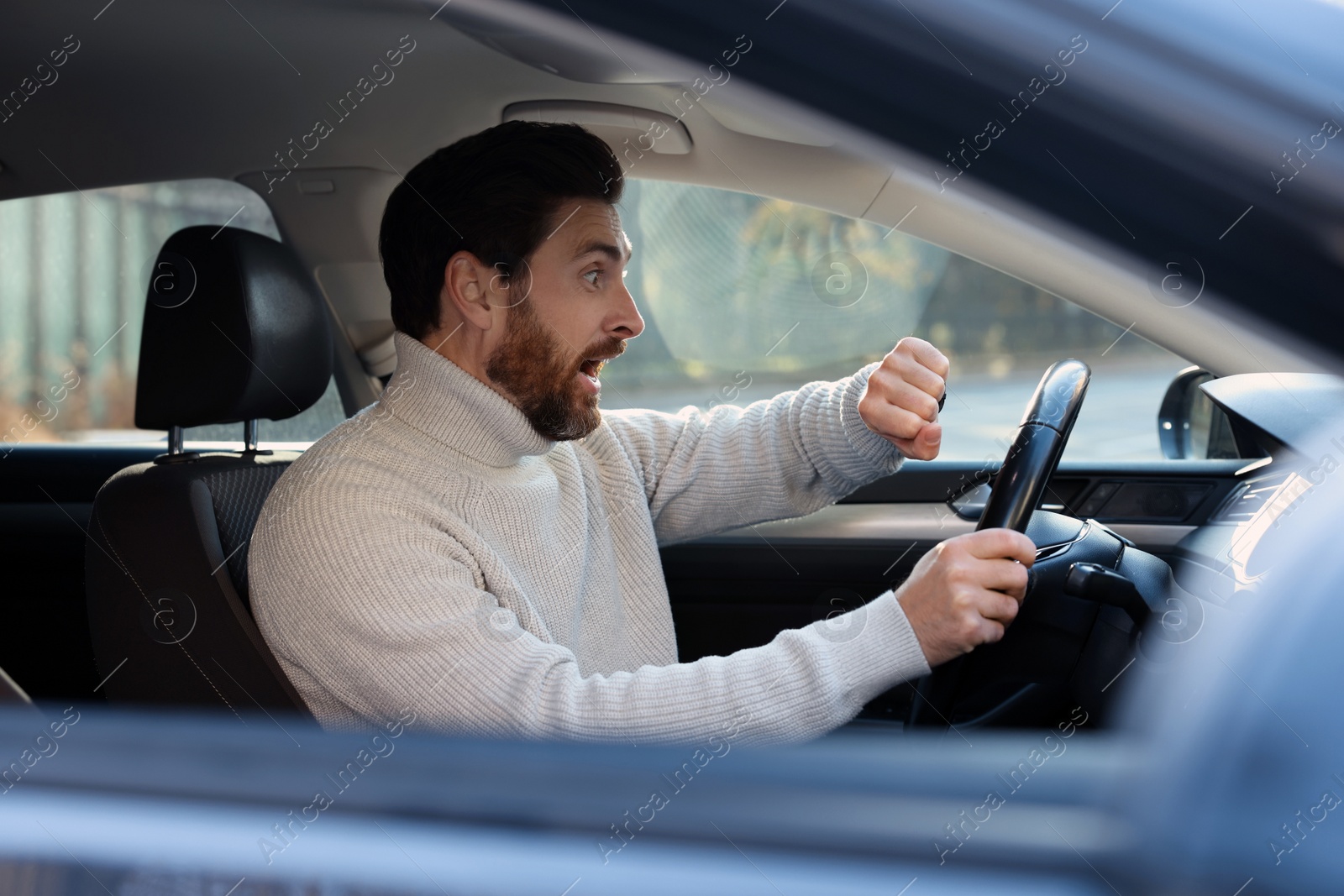 Photo of Emotional man checking time on watch in car. Being late concept