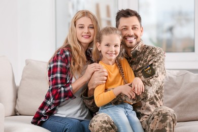 Photo of Soldier in Ukrainian military uniform reunited with his family on sofa at home