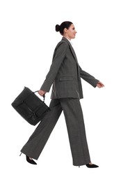 Beautiful businesswoman in suit with briefcase walking on white background