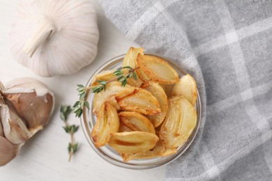Photo of Fried garlic cloves with thyme in bowl on table, flat lay