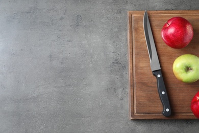 Photo of Flat lay composition with sharp knife, apples and wooden board on grey background. Space for text