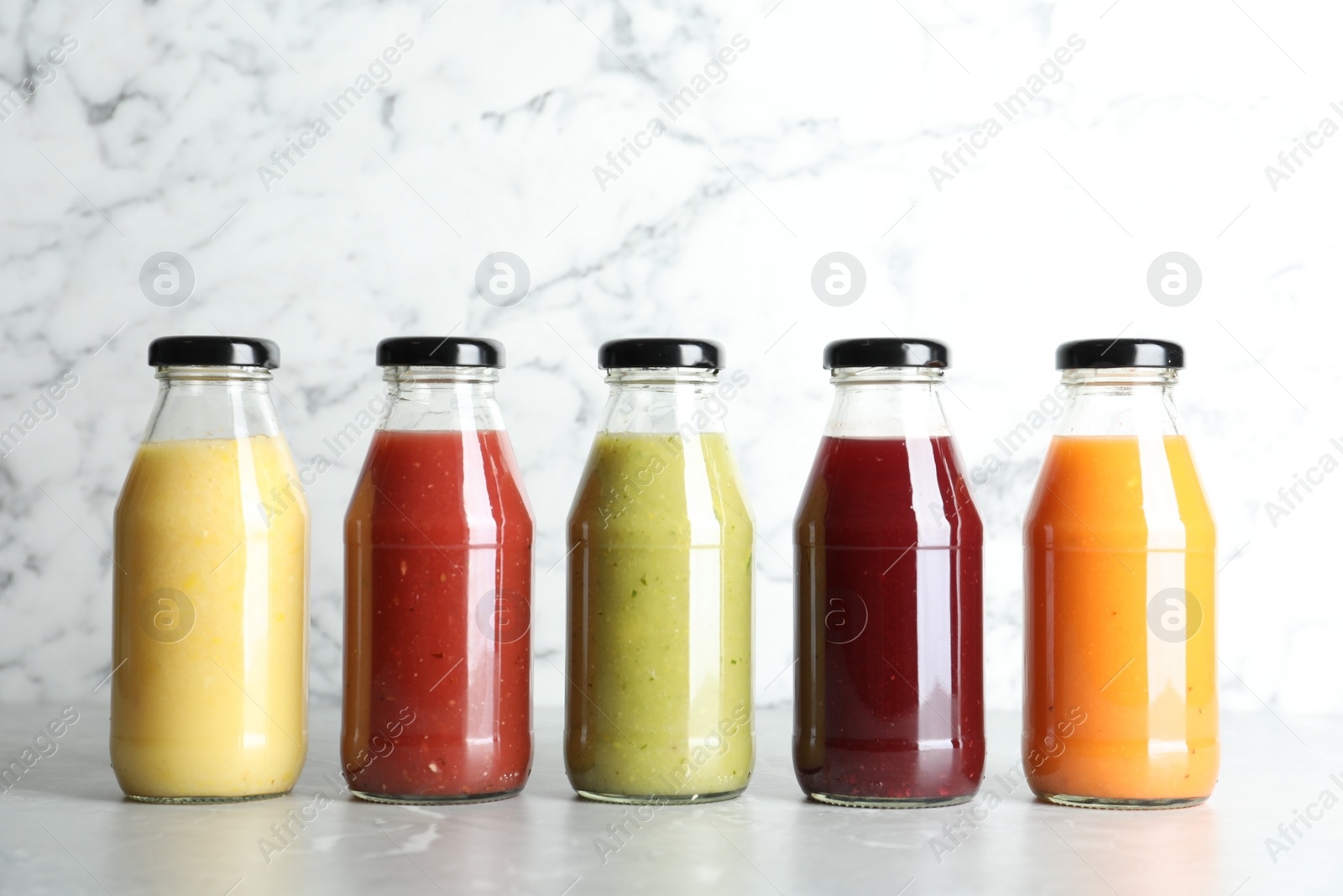 Photo of Bottles with delicious colorful juices on marble table