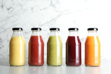 Photo of Bottles with delicious colorful juices on marble table