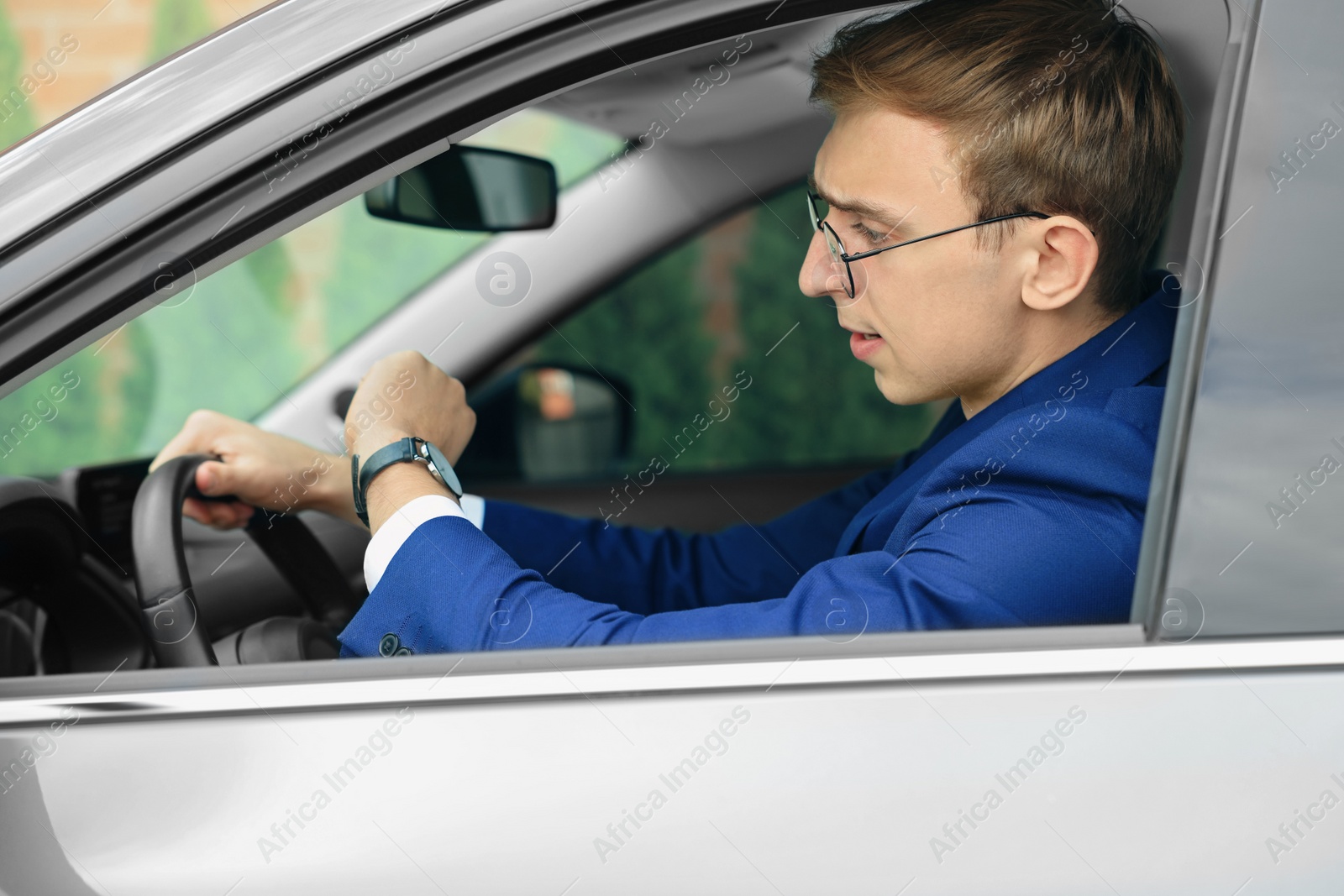 Photo of Young man checking time in car. Being late