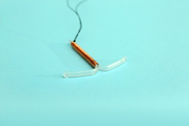 Photo of T-shaped intrauterine birth control device on turquoise background