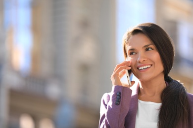 Photo of Beautiful businesswoman talking on phone outdoors. Space for text