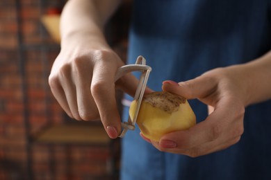 Photo of Woman peeling fresh potato indoors, closeup view