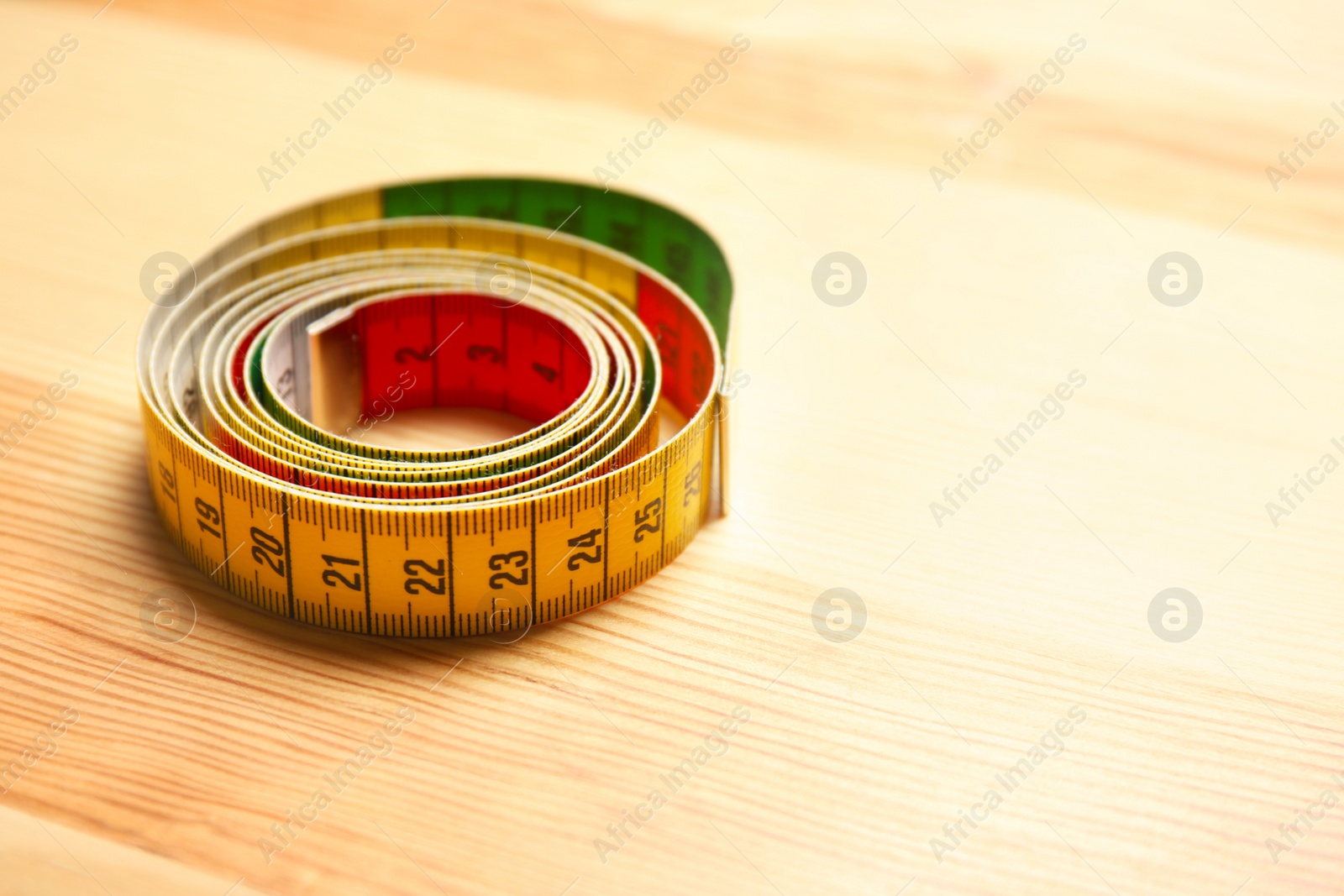 Photo of Rolled measuring tape for tailoring on wooden background