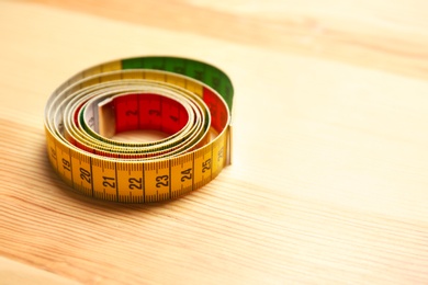 Rolled measuring tape for tailoring on wooden background