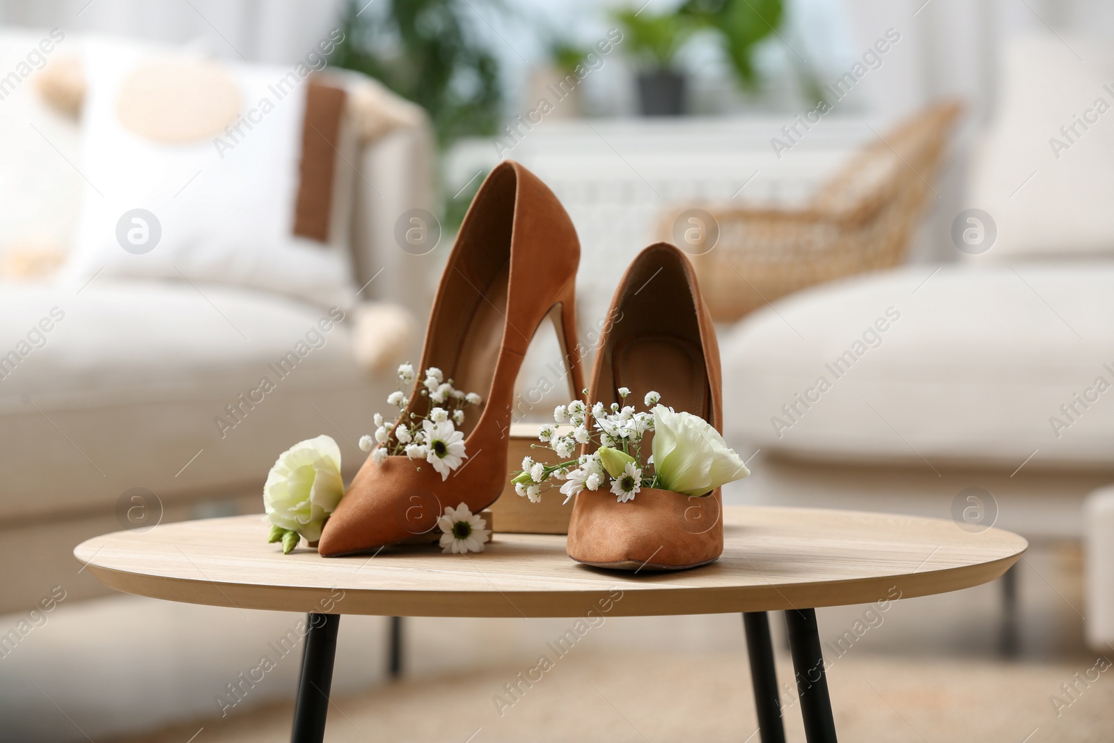 Photo of Women's shoes with beautiful flowers on table indoors
