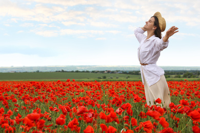 Woman with straw hat in blooming poppy field