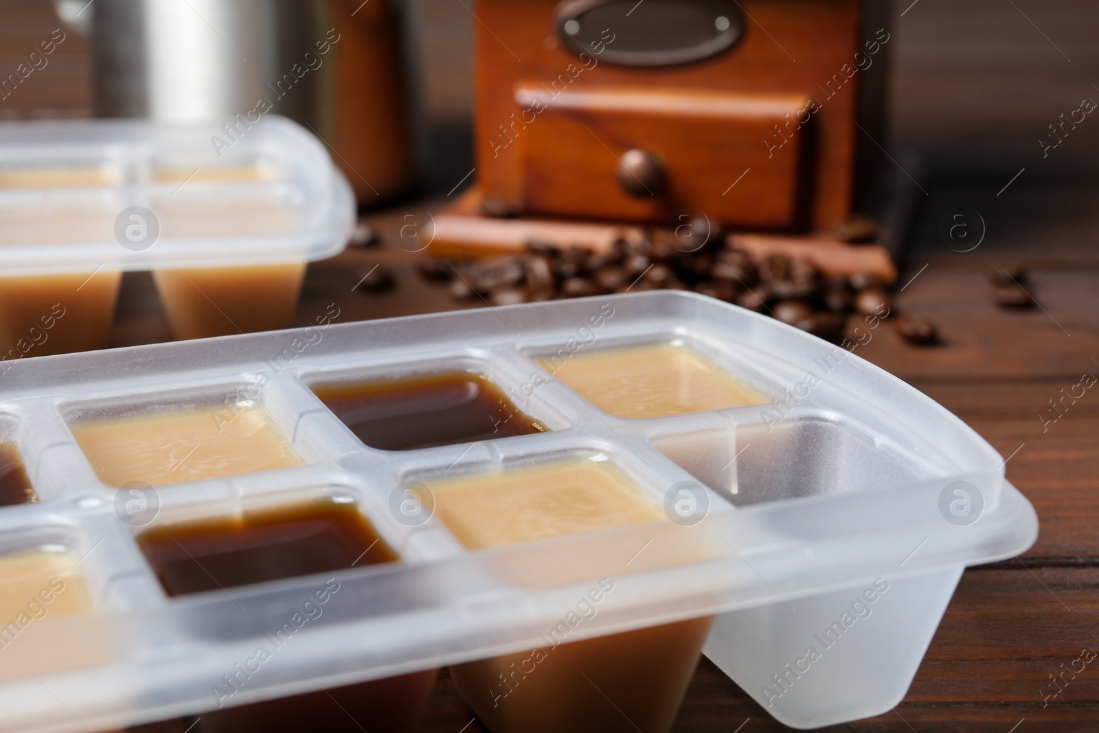 Photo of Ice cube tray filled with coffee drink on table, closeup
