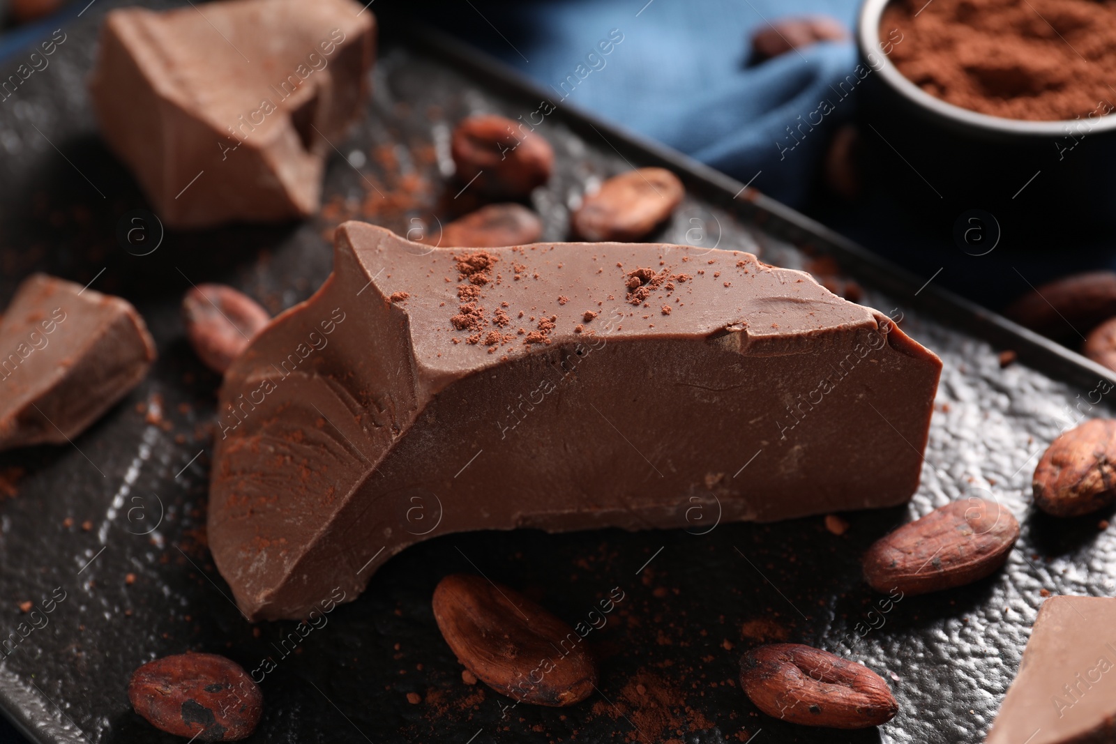 Photo of Pieces of tasty milk chocolate and cocoa beans on table, closeup