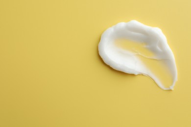 Sample of face cream on yellow background, top view. Space for text
