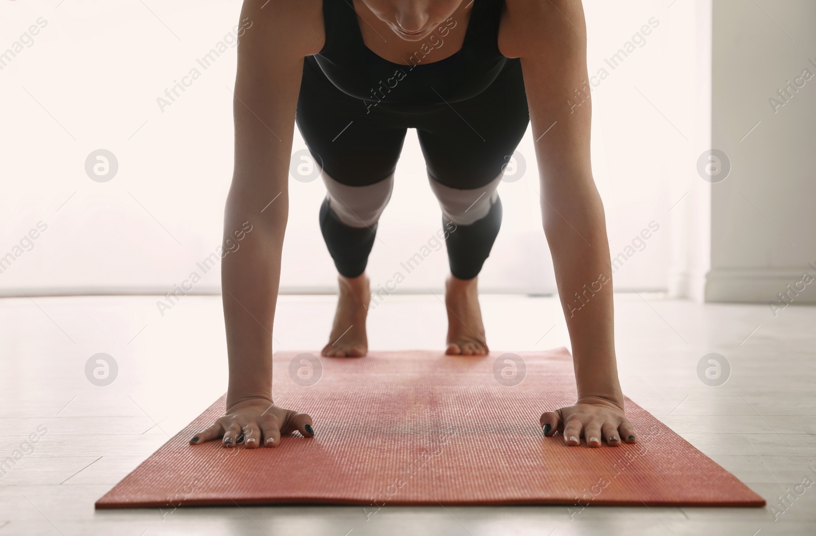 Photo of Woman practicing plank asana in yoga studio, closeup. Phalankasana pose