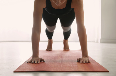 Photo of Woman practicing plank asana in yoga studio, closeup. Phalankasana pose