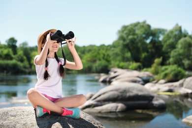 Little girl with binoculars outdoors. Summer camp