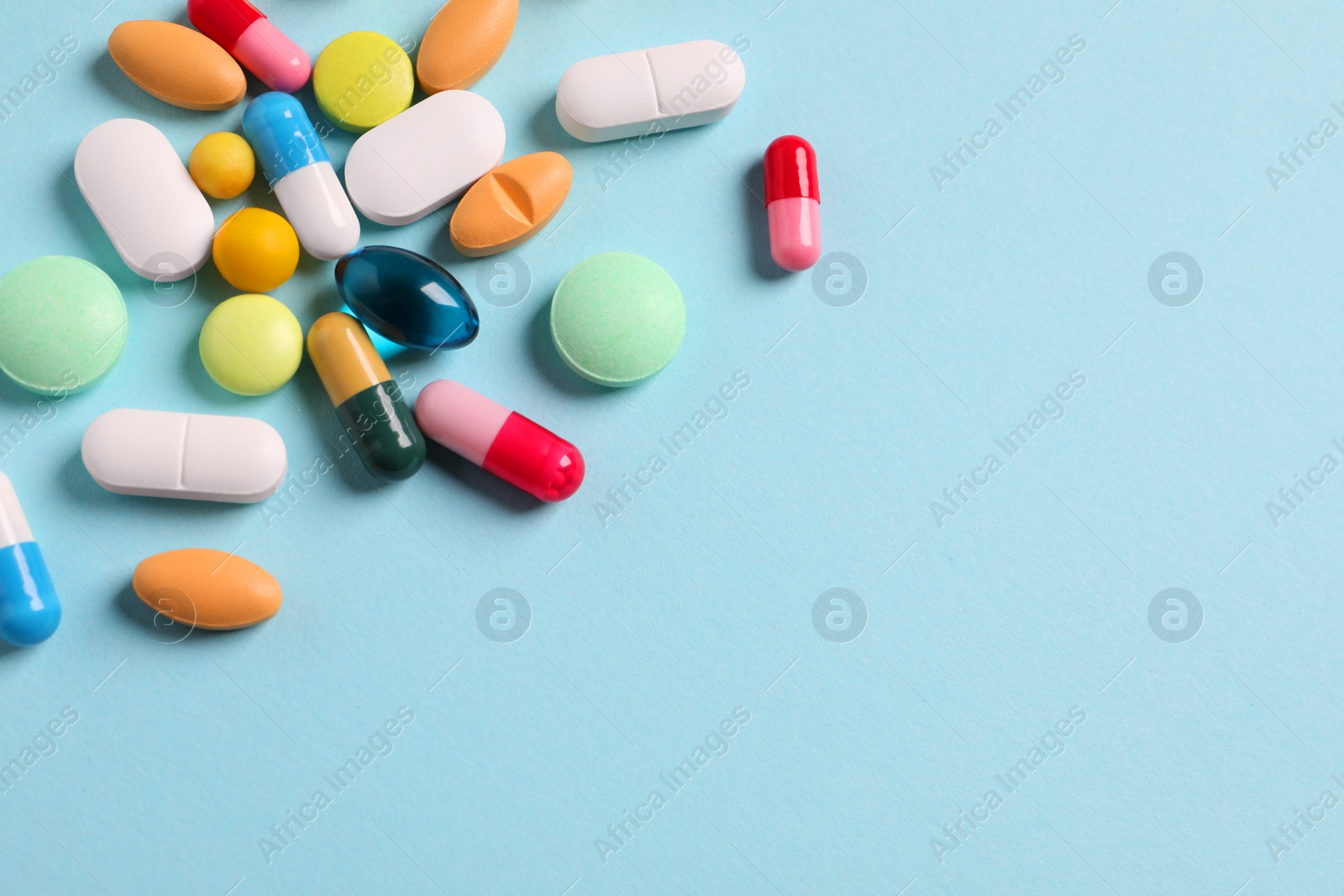 Photo of Many different pills on light blue background, flat lay. Space for text